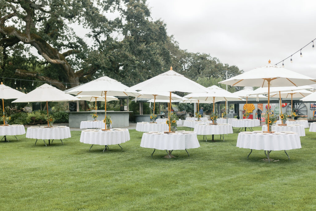 outdoor wedding venue with white tables and white umbrellas for a summer wedding in the Bay Area with lush forest in the distance 