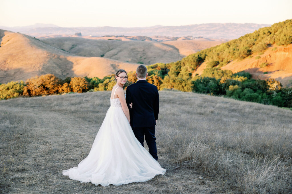 bride and groom walking towards the hillside at sunset at Rosewood events photographed by Bay Area wedding photographer