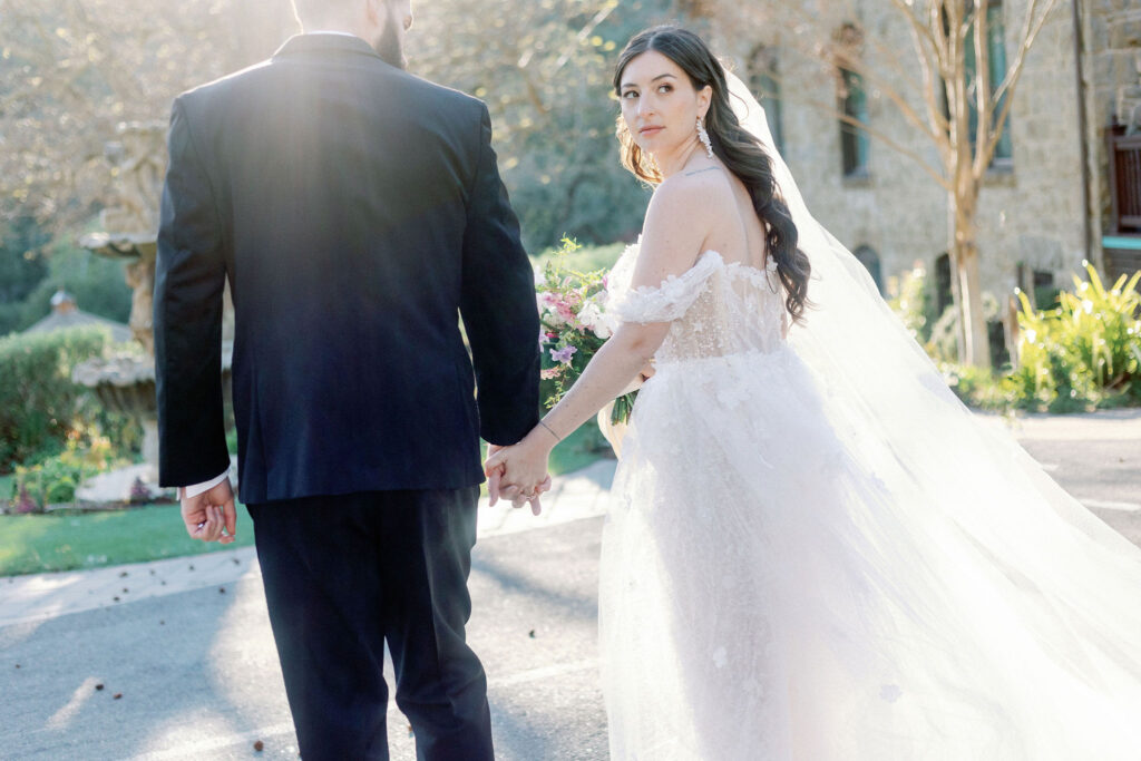Bay Area photographer captures bride and groom holding hands while bride looks over shoulder
