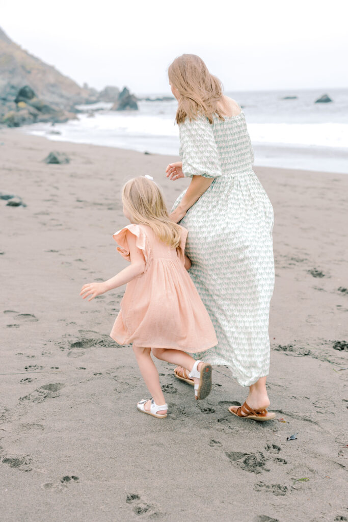 Bay Area wedding photographer captures mother holding child's hand while running through sand