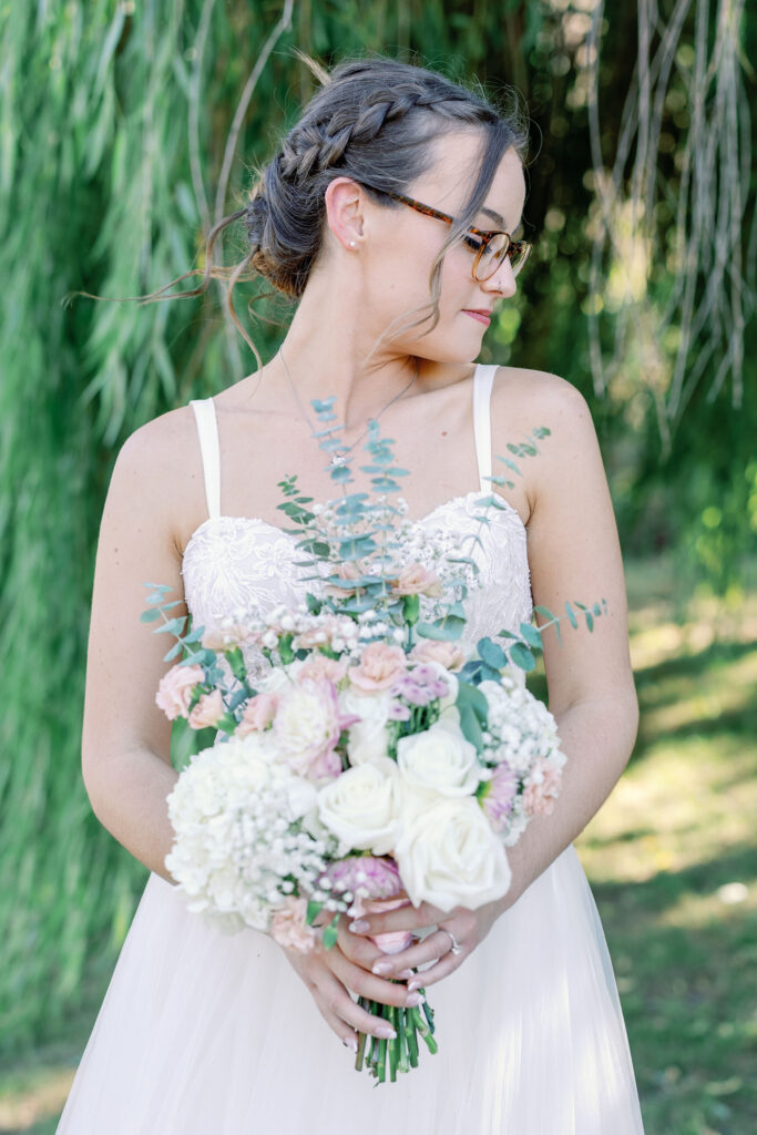 bridal portrait photographed by bay area wedding photographer with bride holding her rose bouquet to her chest and looking over her shoulder at Rose Wood events wedding 
