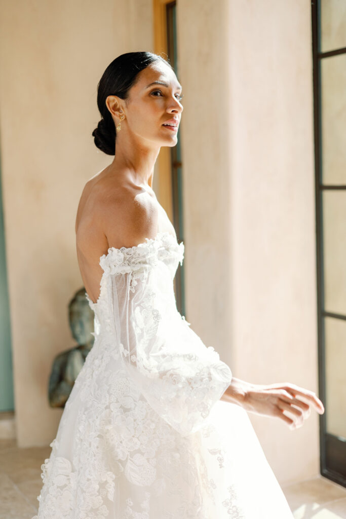 bride with a slicked-back bun at the nape of her neck as she walks through a pair of french doors in her bridal suite documented by Bay Area wedding photographer