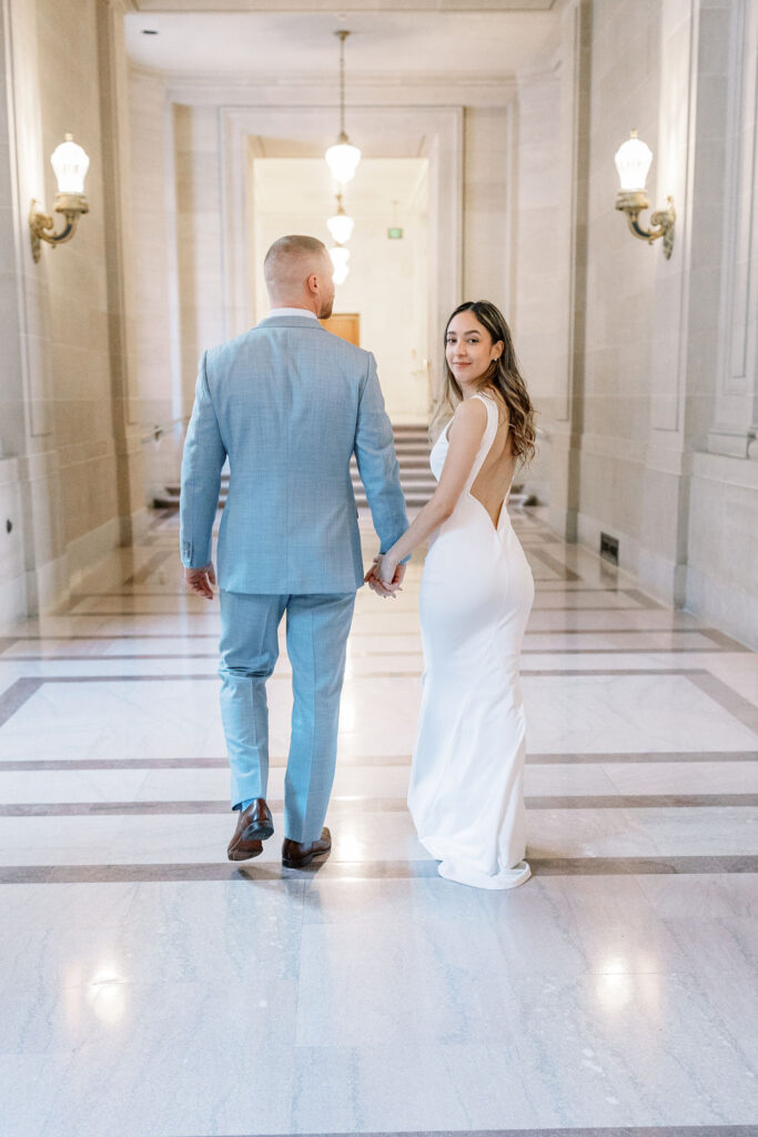 Bay Area wedding photographer captures bride and groom holding hands while looking over shoulder
