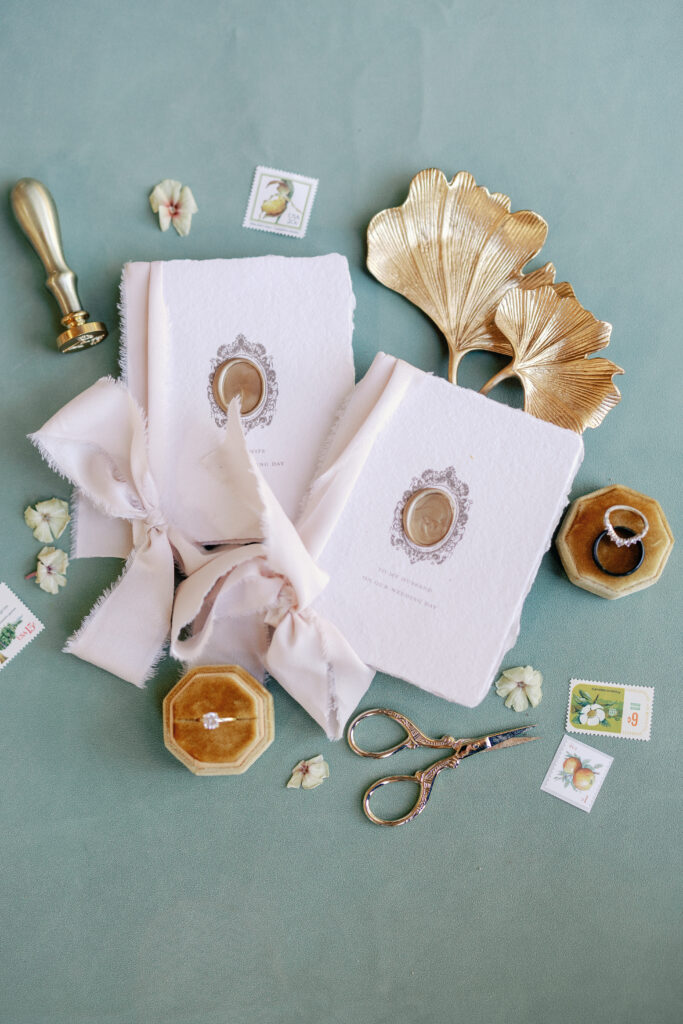 wedding details flatlay with invitation suite, stamp and florals 